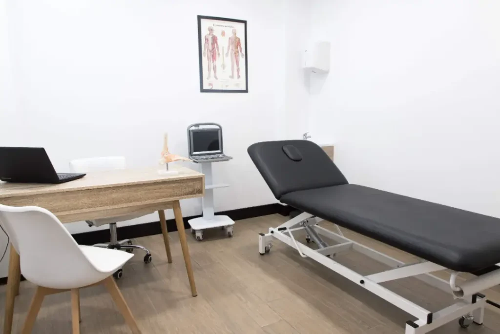 Camilla de fisioterapia junto a un escritorio de consulta